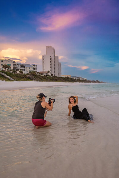 Behind The Scenes Senior Portrait Session in Seaside Florida at Sunset Seaside photographer behind the scenes capturing senior in black gown in surf at sunset