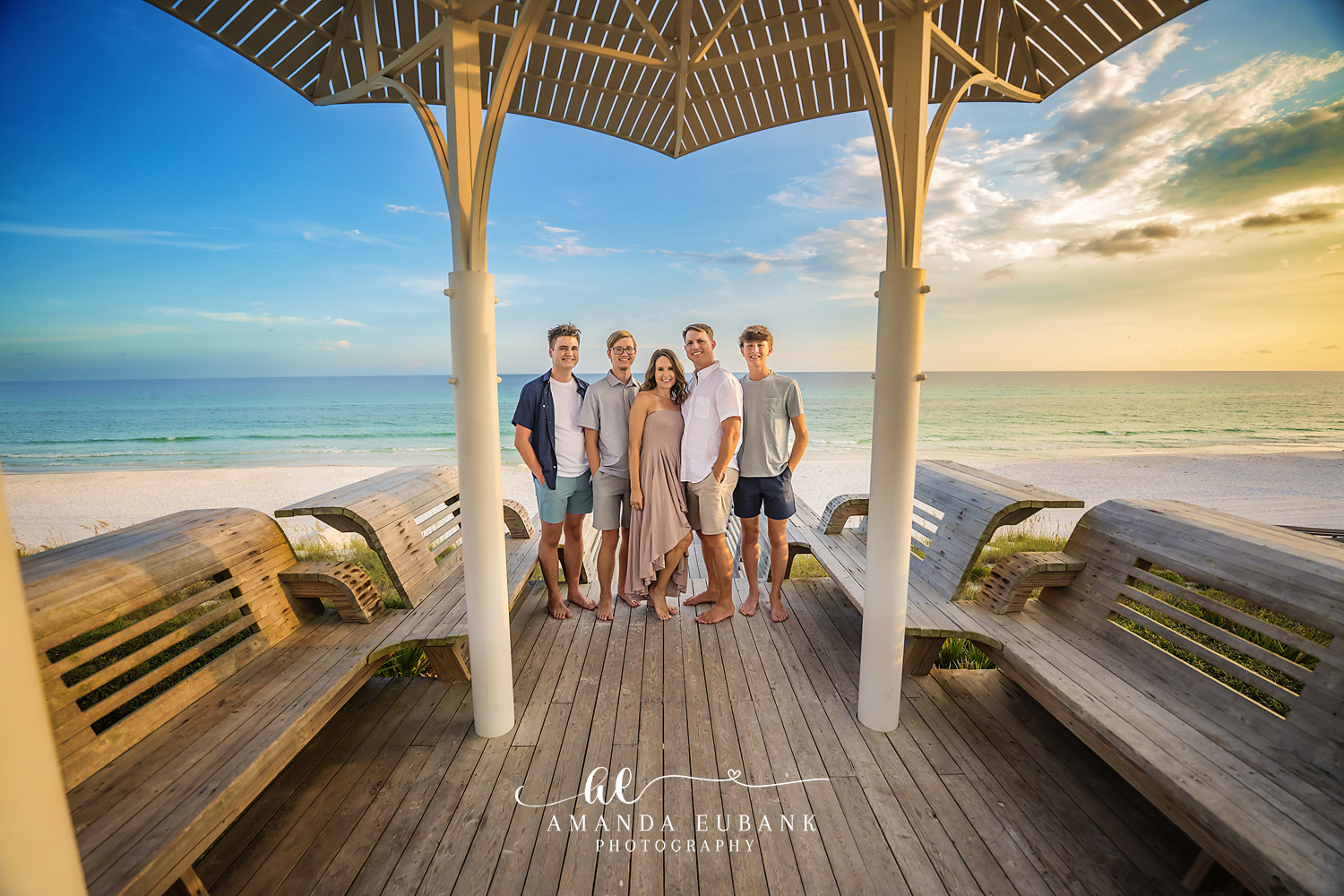 Family posing together on the beach with a colorful sunset sky in Seaside Florida
