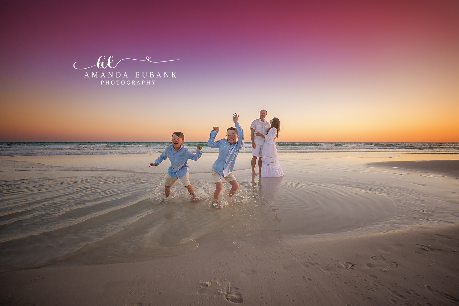 Two young boys jumping and leaping in the ocean waves at a golden pink twilight sunset in Seaside Florida