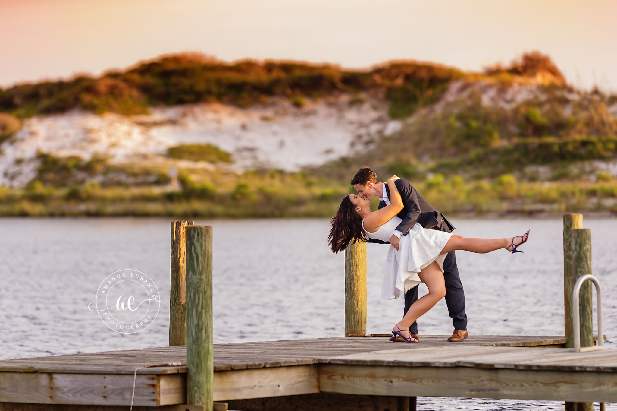 Seaside engagement photographer captures dip kiss on wooden dock by the water