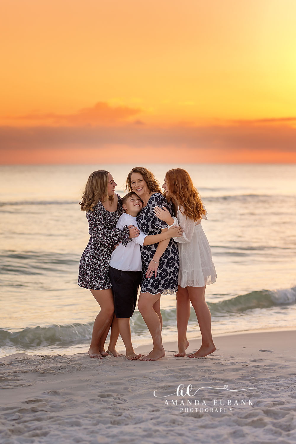Mom laughing with two teenage daughters and a young son on the beach at a blazing orange sunset in Seaside Florida