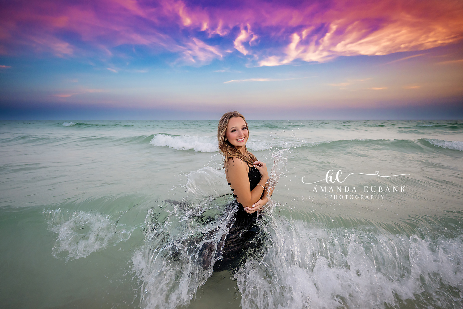 Seaside Florida senior photographer captures senior in black dress in crashing waves at sunset