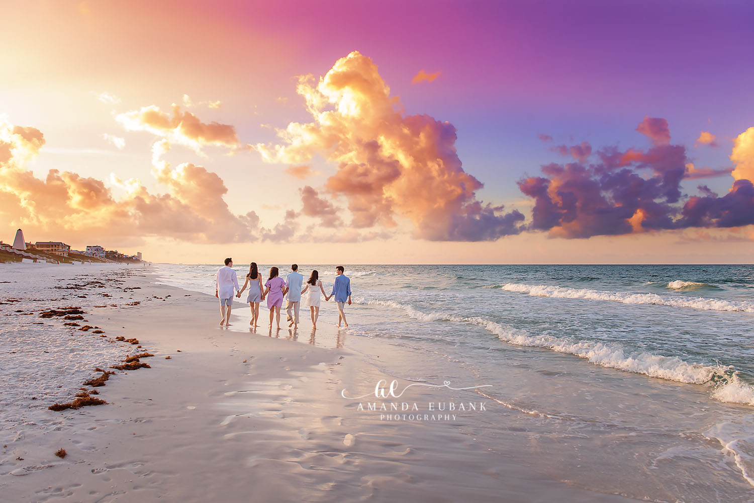 Family of five walking away from camera down the beach at a golden and purple dramatic sunset in Seaside Florida