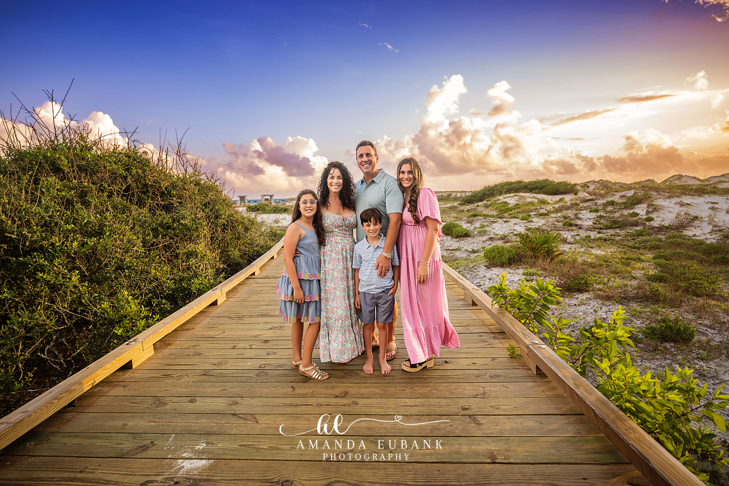 Seaside family photographer captures family of five on dune boardwalk at golden sunset