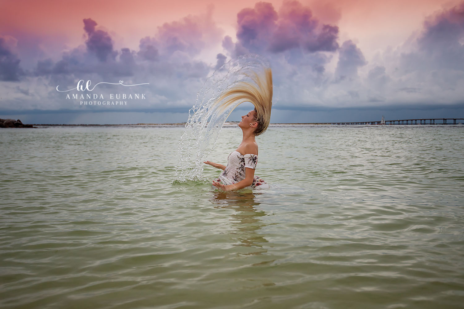 Seaside senior photographer captures dramatic hair flip splash senior portrait in calm bay water