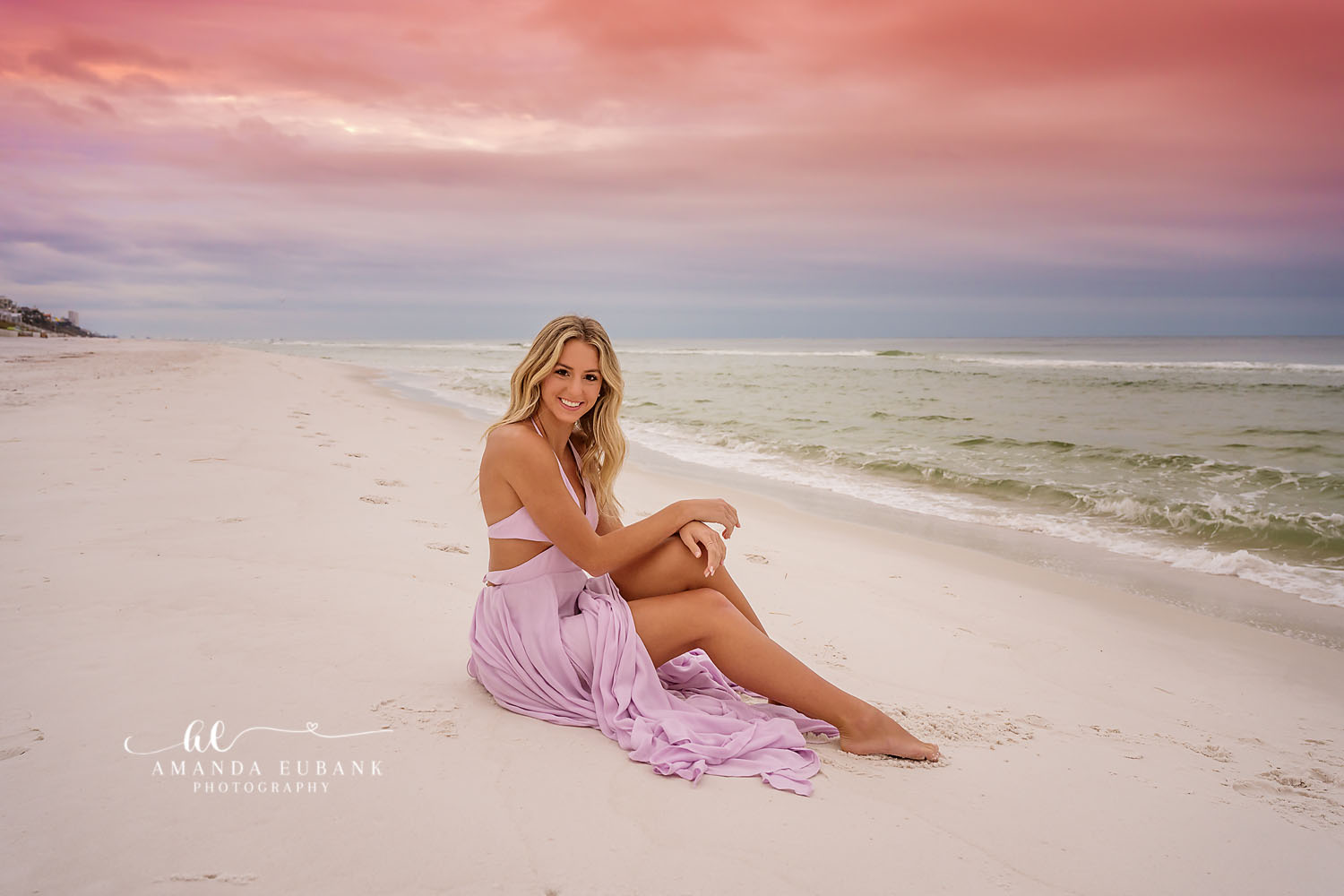 Seaside senior photographer captures senior in flowing lavender dress on the beach at sunset