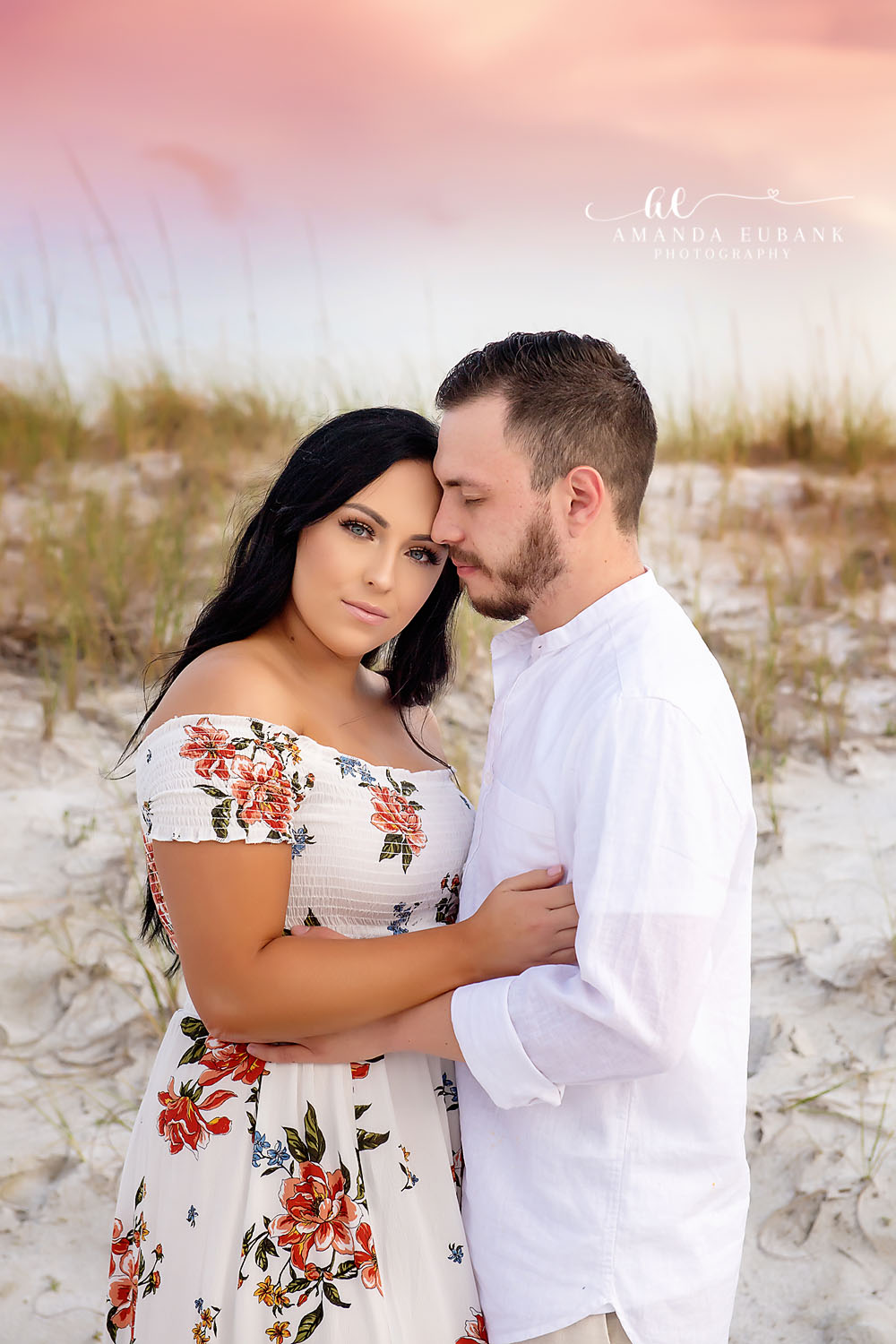 Couple in a tender embrace on the beach at a beautiful pastel pink and lavender sunset in Seaside Florida with the calm Gulf of Mexico