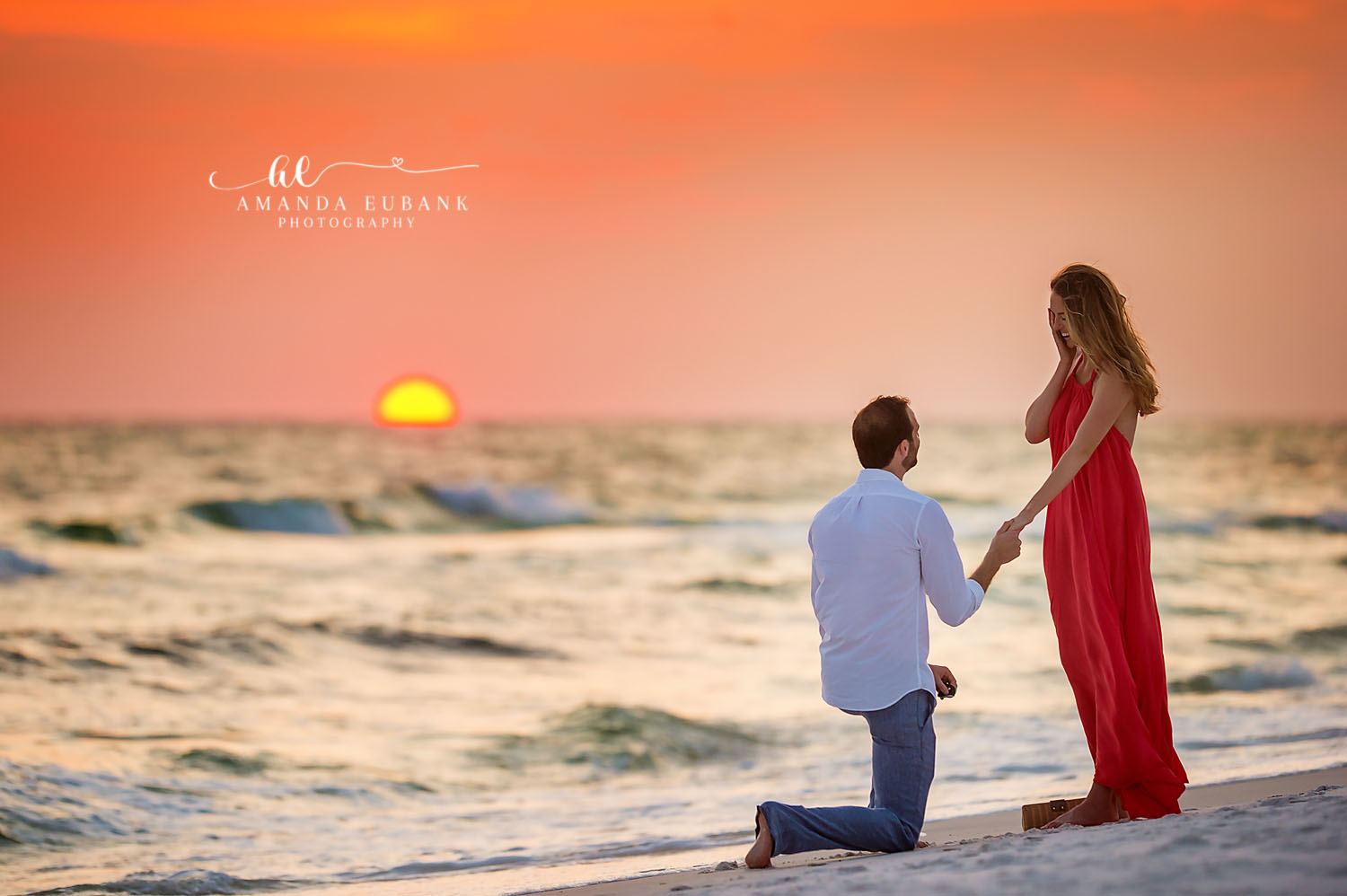 Engaged couple dancing and spinning joyfully on the beach at a blazing orange and red sunset in Seaside Florida