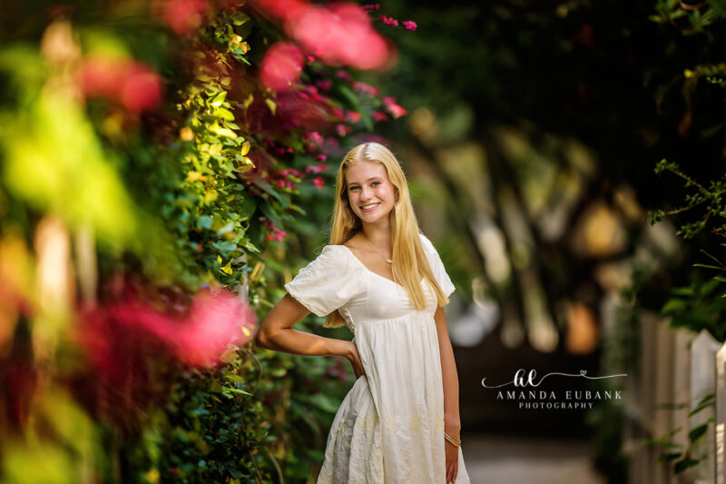 Blonde senior girl at the beach with a vivid colorful pink and golden sunset sky in Seaside Florida