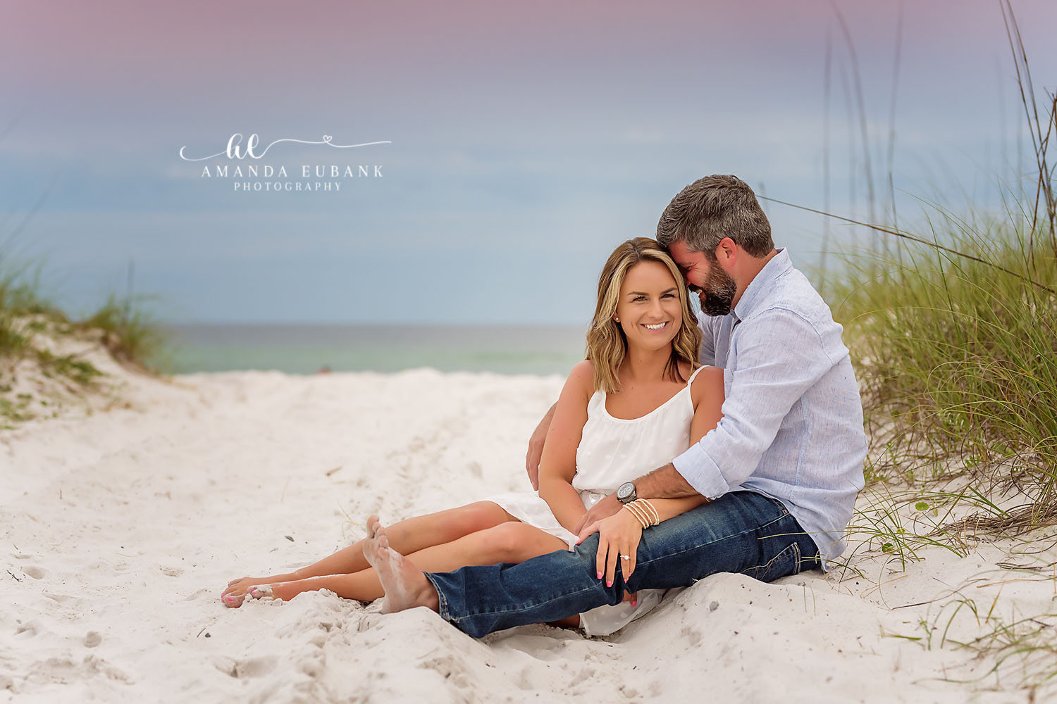 Engaged couple in a romantic embrace on the beach with a blazing orange and red sunset sky behind them in Seaside Florida
