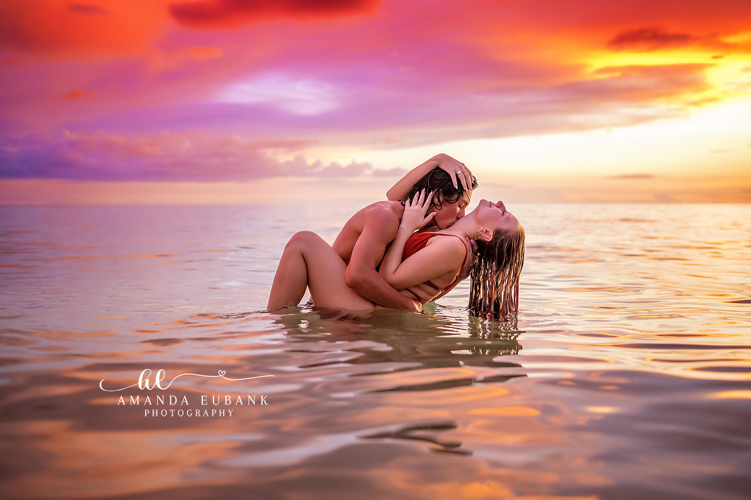 Engaged couple facing each other in a loving embrace on the beach with a stunning pastel purple and pink sunset behind them in Seaside Florida