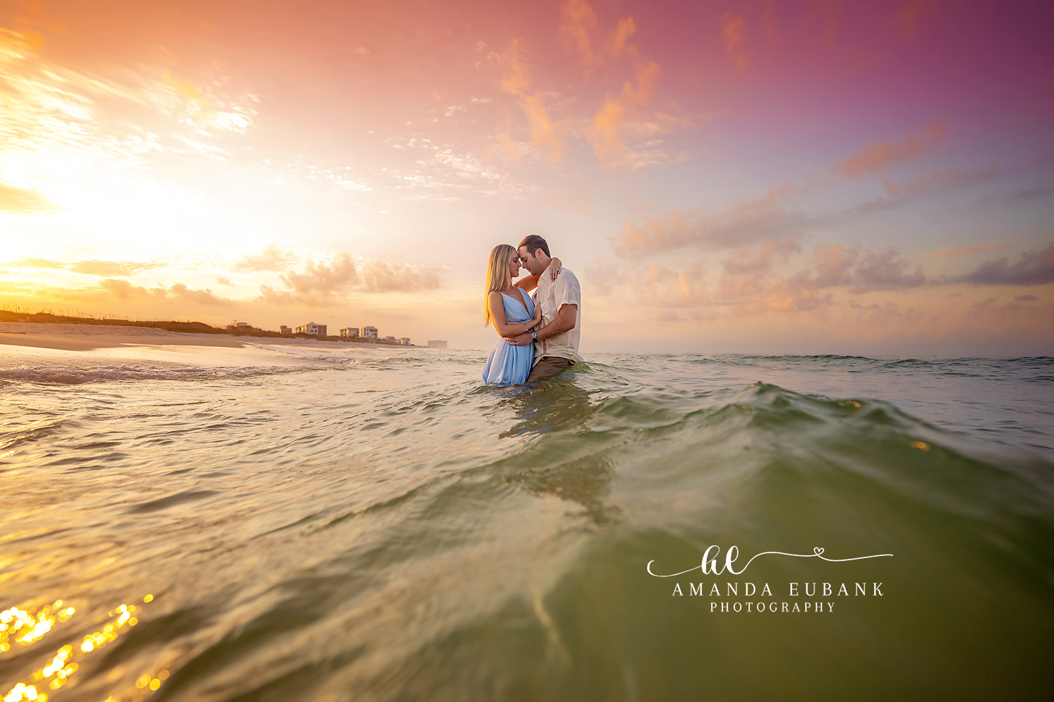 Engaged couple raising their arms in joy and celebration on the beach at a pastel pink and purple sunset in Seaside Florida