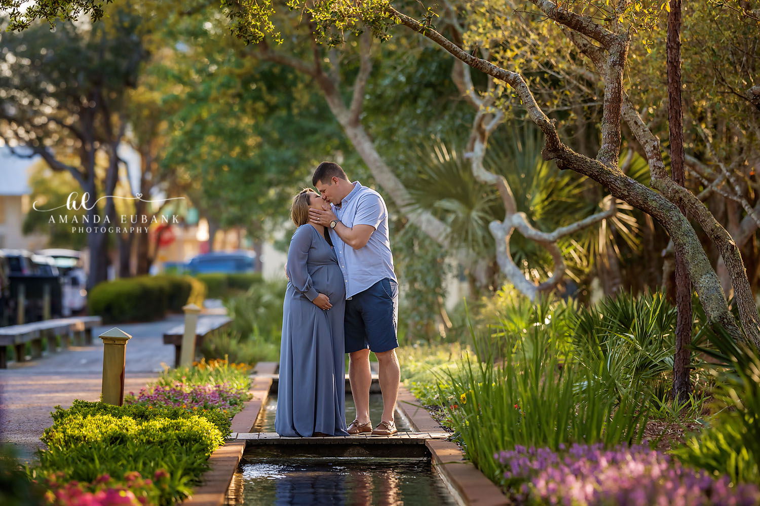 Seaside Florida maternity photographer captures expecting couple sharing a kiss in a lush garden setting