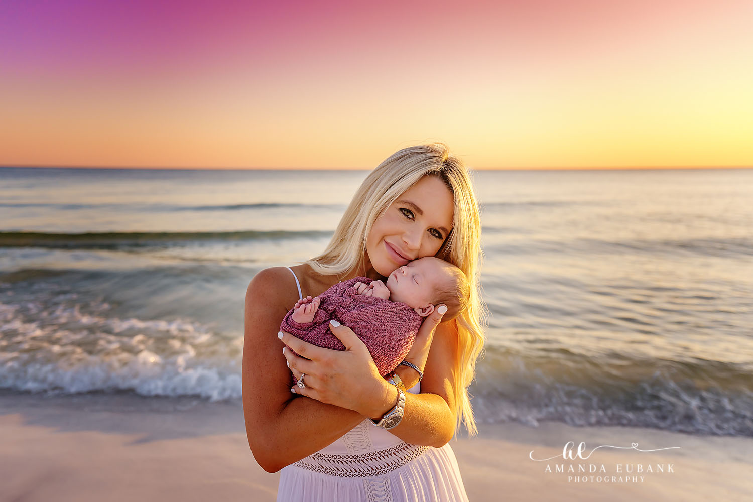 Tiny newborn wrapped in soft pink photographed on the beaches of Seaside Florida at golden hour
