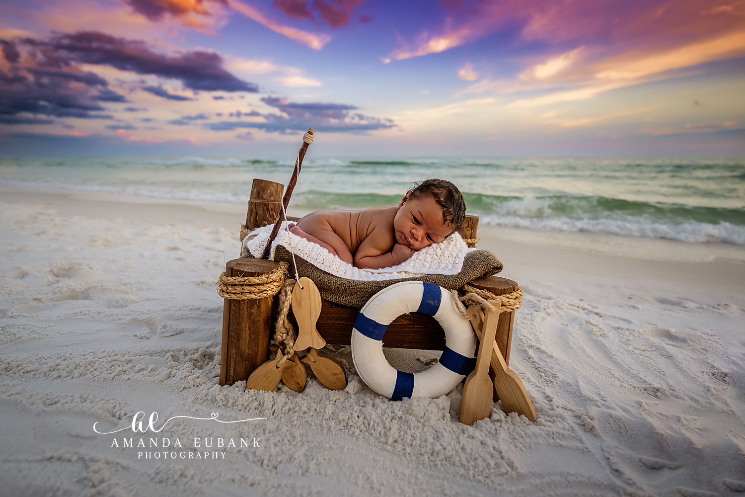 Seaside Florida newborn photographer captures sleeping baby in wooden bowl on the beach at a glowing sunset