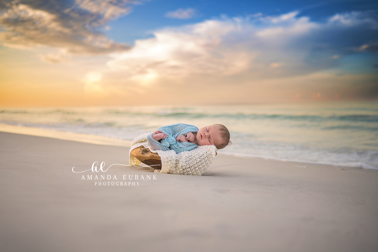 Newborn beach portrait session by Seaside photographer Amanda Eubank with emerald water and pastel sky