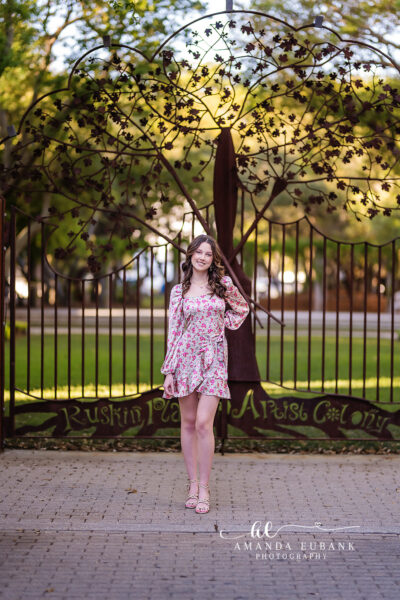 Senior girl with dark brown wavy hair in a colorful striped crochet top and pink skirt posing at a beautiful outdoor setting in Seaside Florida